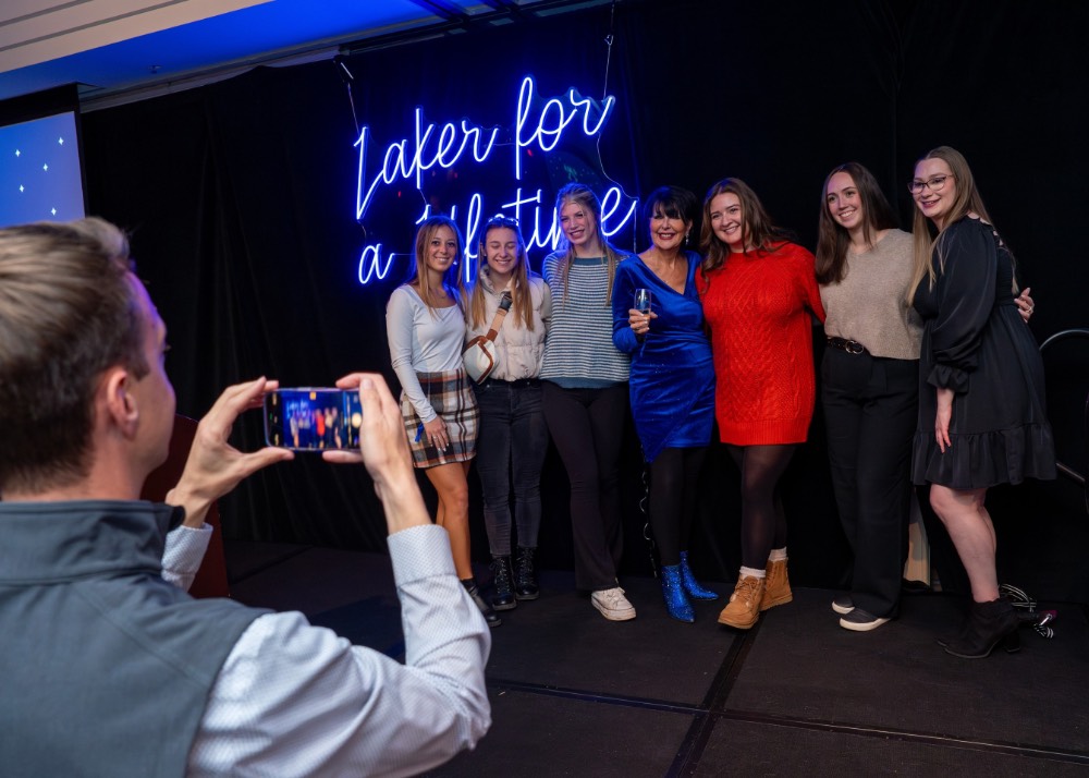 Big group of girls pose on stage with President Mantella